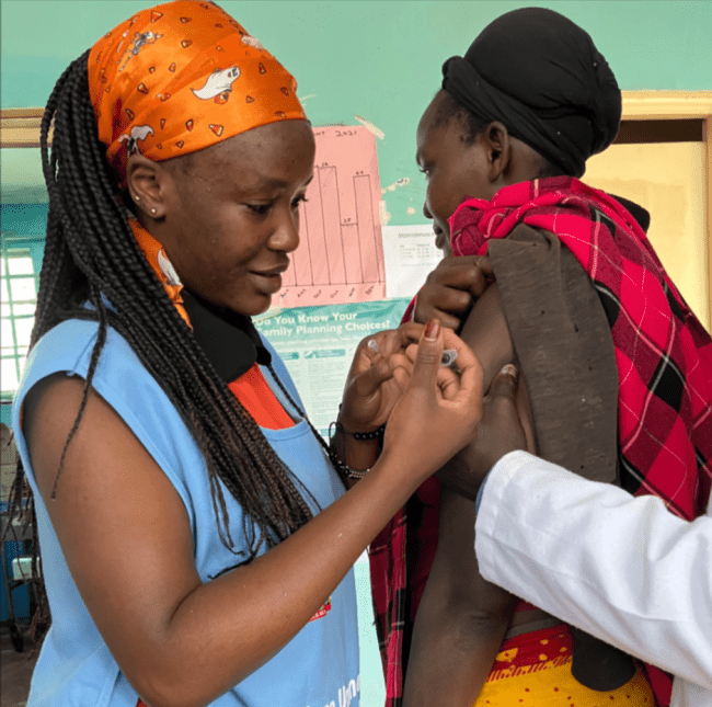 a young Black woman administers a vaccine to another Black woman