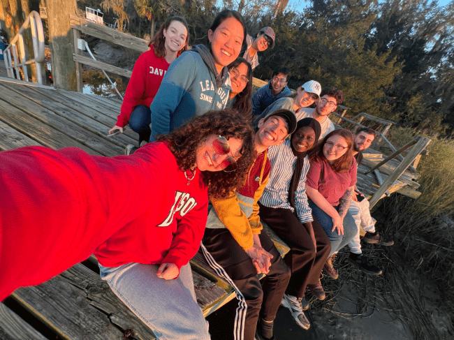 a group of young men and women take a picture together on a dock