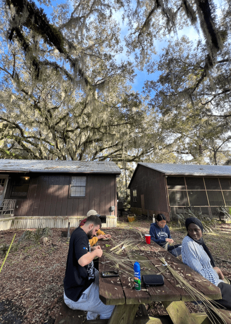 a group of young people basket weaving outside
