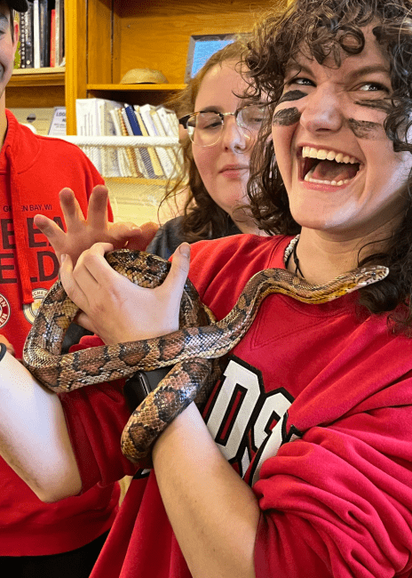 a young woman holds a snake and smiles