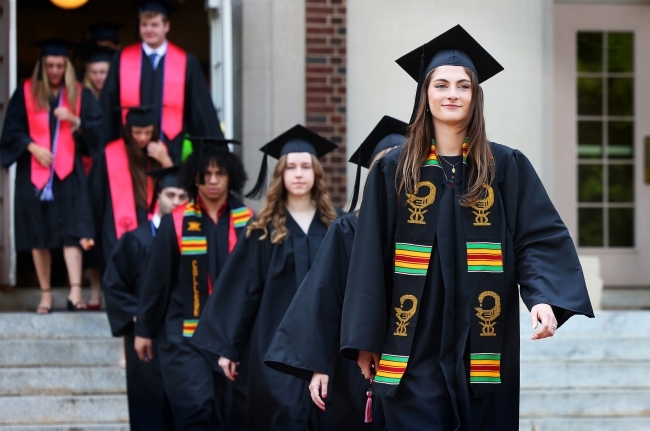 students in graduation robes process