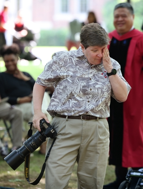 a middle aged woman wiping a tear while holding a camera