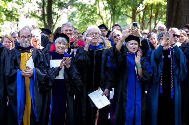 a group of professors in academic regalia cheer and smile