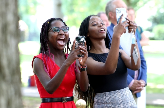 a group of young women cheer while holding phones