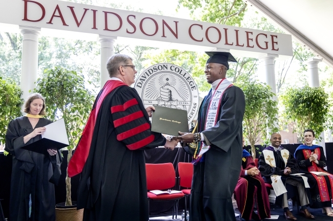 a young man accepts diploma from an older man