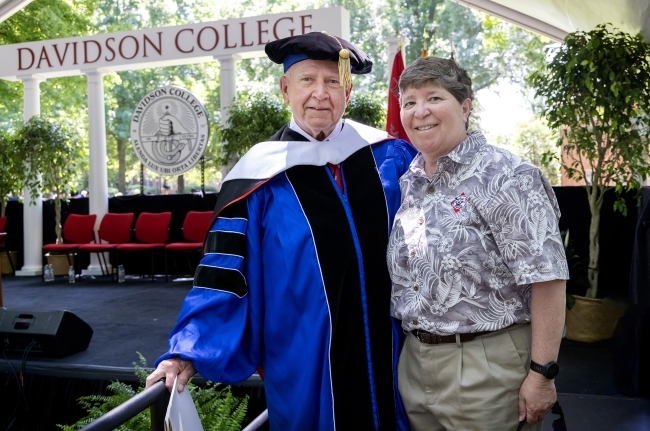 an older man and a middle aged woman stand together in front of a stage