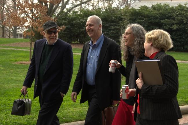 four older people walk together on a college campus smiling and talking