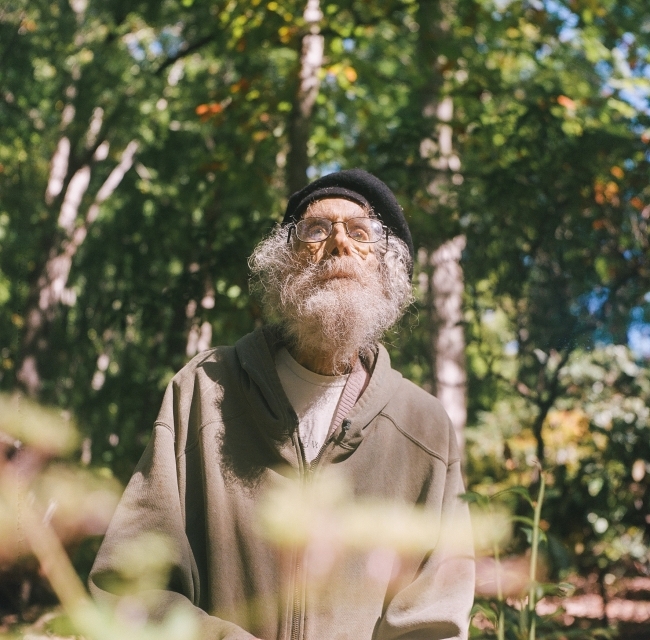 an older man in the woods waring a hat and glasses