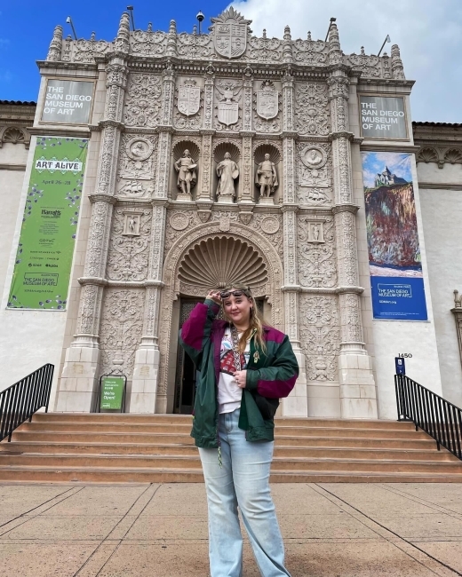 a young white woman stands in front of an art museum