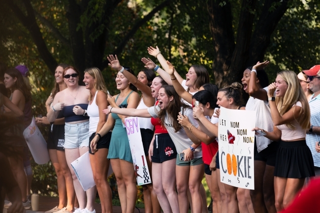 a group of people cheer with signs along a road race