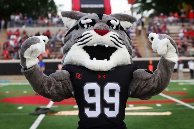 Roary the Wildcat flexes biceps at a Football game