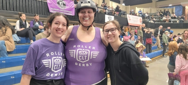 three young women standing together in skates and helmets