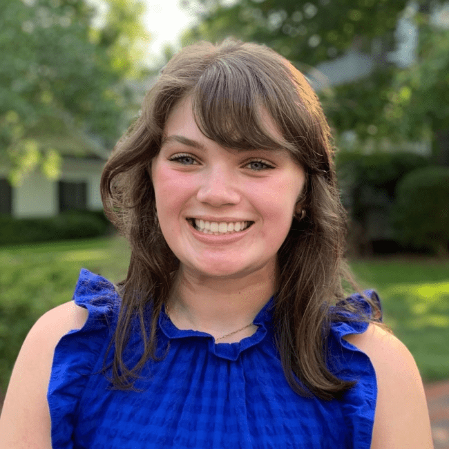 a young white woman with brown hair wearing a blue dress