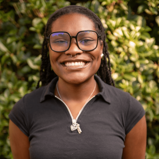 a young Black woman wearing glasses and a black collared top