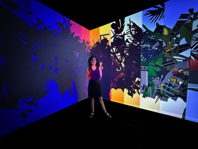 a woman stands in front of a digital screen in an art gallery with vivid colors