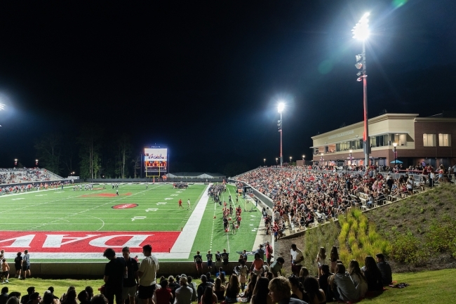 a nighttime football game under the lights in a stadium