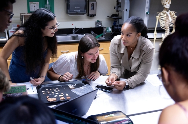 a group of students and professor gather around a table in a lab