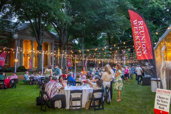 a seated dinner under string lights on a college campus
