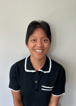 a young person with short brown hair wearing a black and white collared shirt and gold earrings