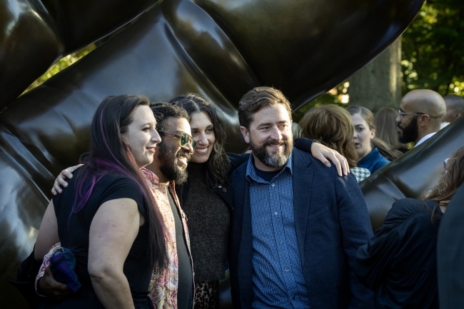 Smiling group of young adults in front of the sculpture