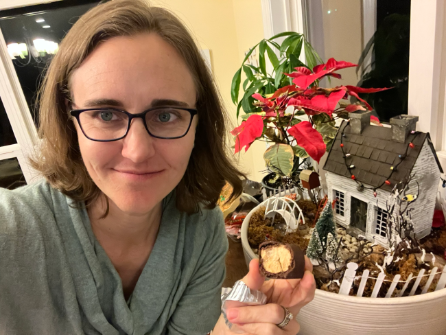 A woman holds a half-eaten cookie in front of a holiday display