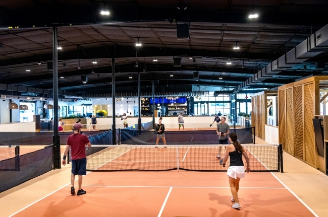 an indoor pickleball court where four people play