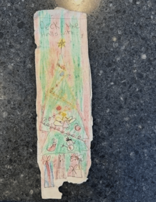 A bookmark made by a young child with a hand-drawn christmas tree in crayon