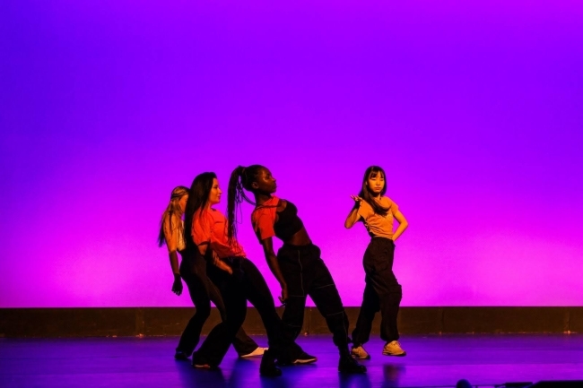a group of young women dance on stage