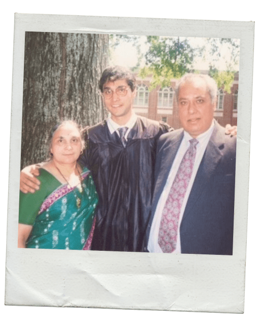 a college student in graduation robes with his parents