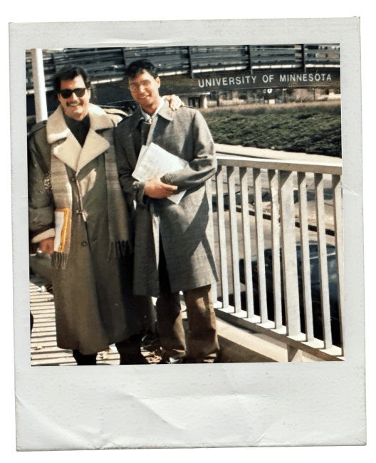 a student and faculty member stand together in front of a building that reads "University of Minnesota"