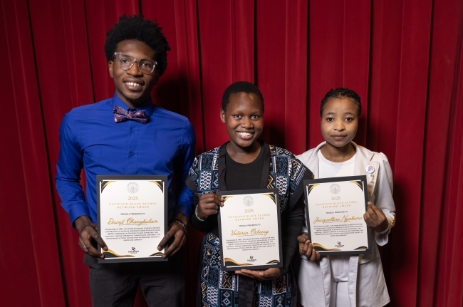 a group of three young people holding awards in front of a red curtain