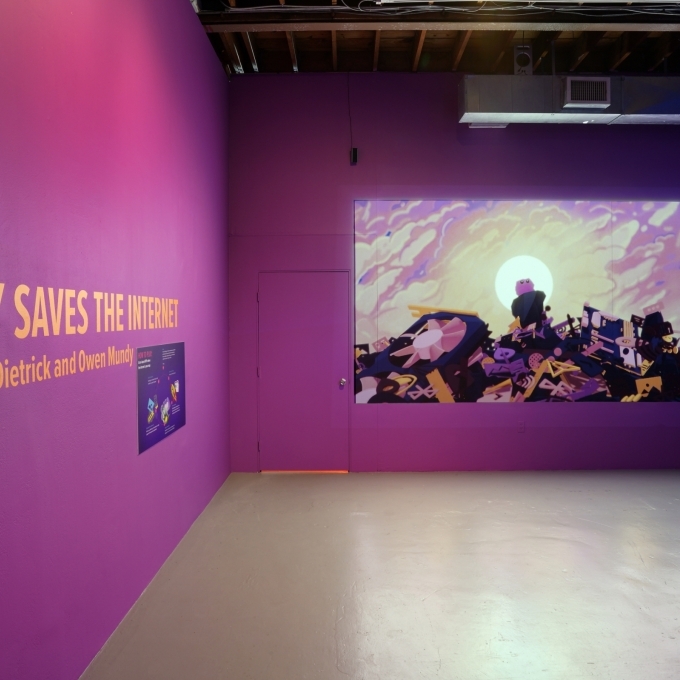 Tally Saves the Internet Exhibit text on wall in purple room, with screen projecting creature on pile of rubble