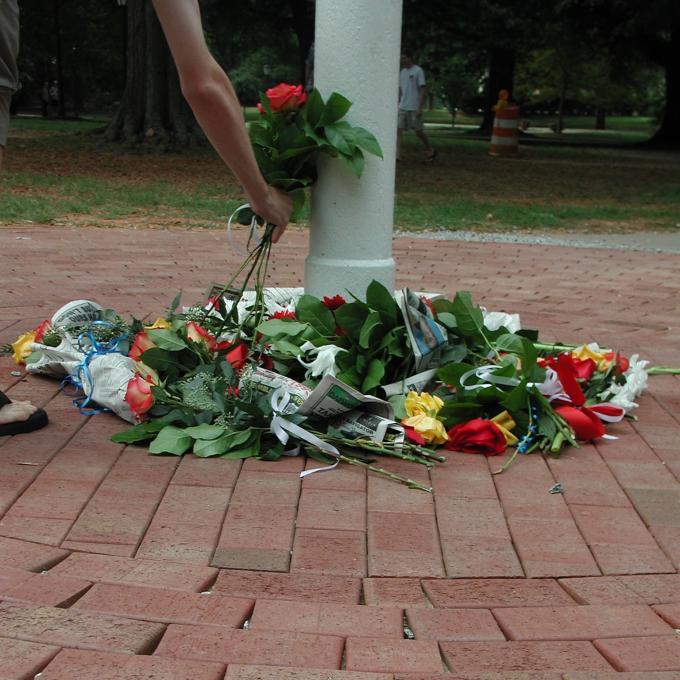 roses and flowers scattered on ground around flagpole in front of Chambers