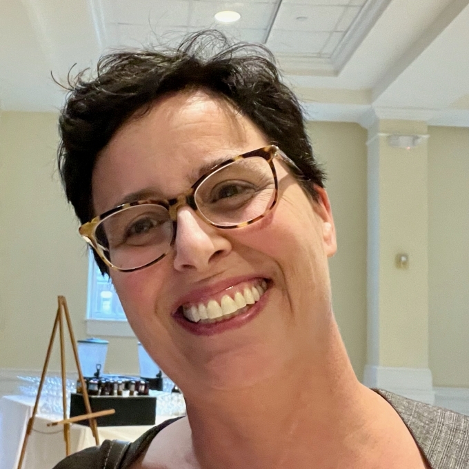 Woman smiling at camera with short black hair and glasses
