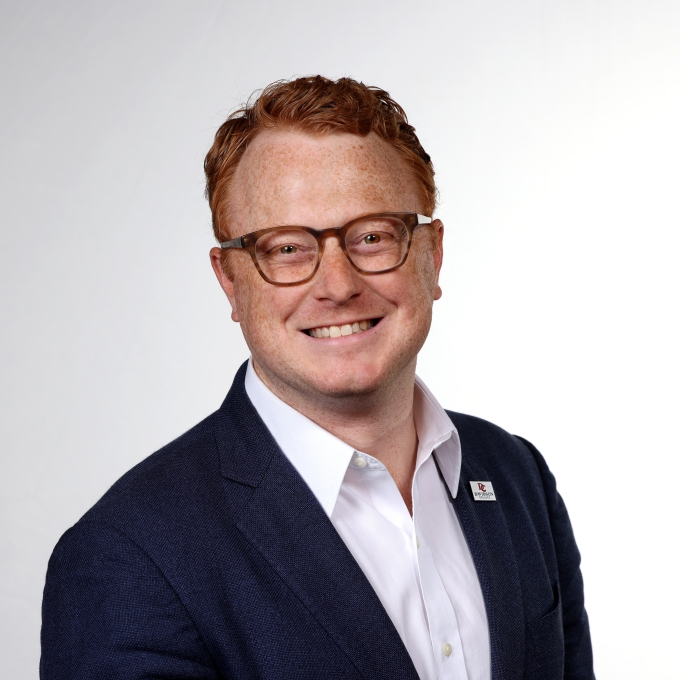 a young white man with red hair wearing glasses