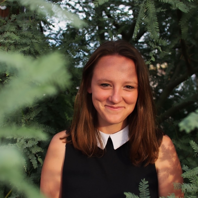 a young white woman wearing a black top with a white collar and smiling