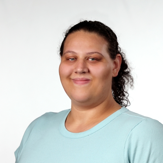a young woman with curly dark brown hair wearing a light teal top
