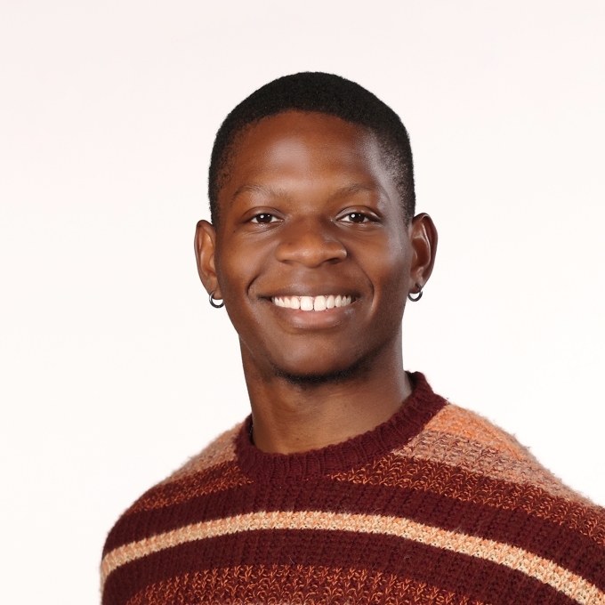 a young Black man wearing a striped sweater