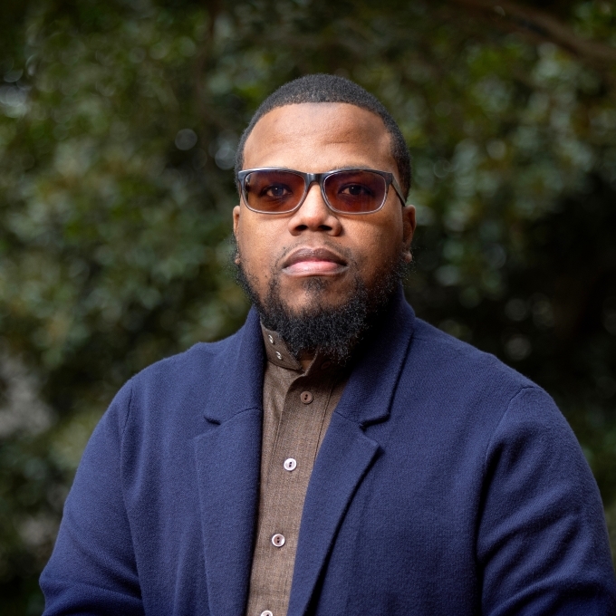 a young Black man wearing a collared shirt and blazer