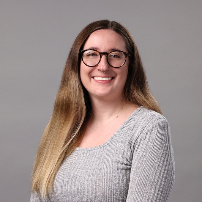 a young white woman wearing glasses and a grey top