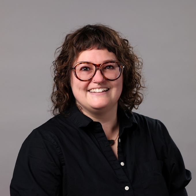 a young white woman with curly brown hair wearing a black buttoned top