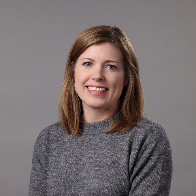 a middle aged white woman wearing a grey sweater
