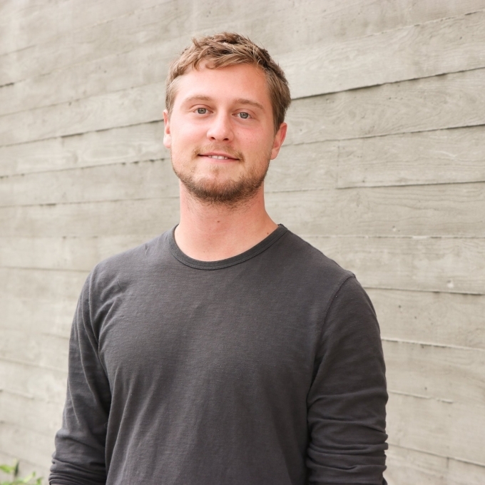 a young white man with blonde hair wearing a long sleeved grey shirt