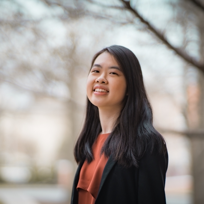 a young Asian woman with long dark hair wearing a red top and black blazer