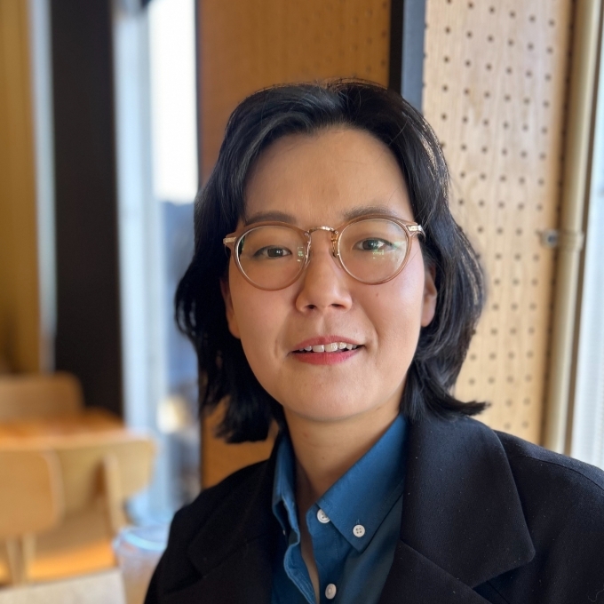 a young professor with glasses wearing a collared shirt and blazer with short brown hair