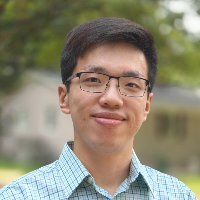 a young Asian man wearing a collared shirt and glasses