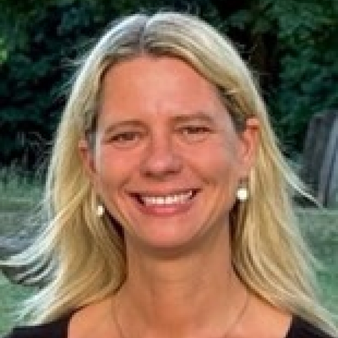 a woman with blonde hair wearing a black top and smiling outside
