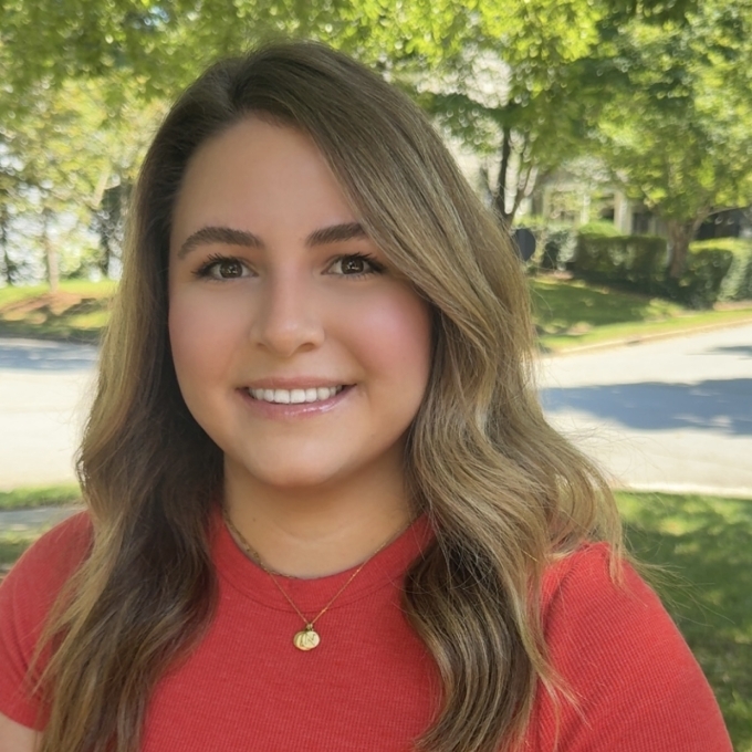 a woman with short brown curly hair wearing a red top