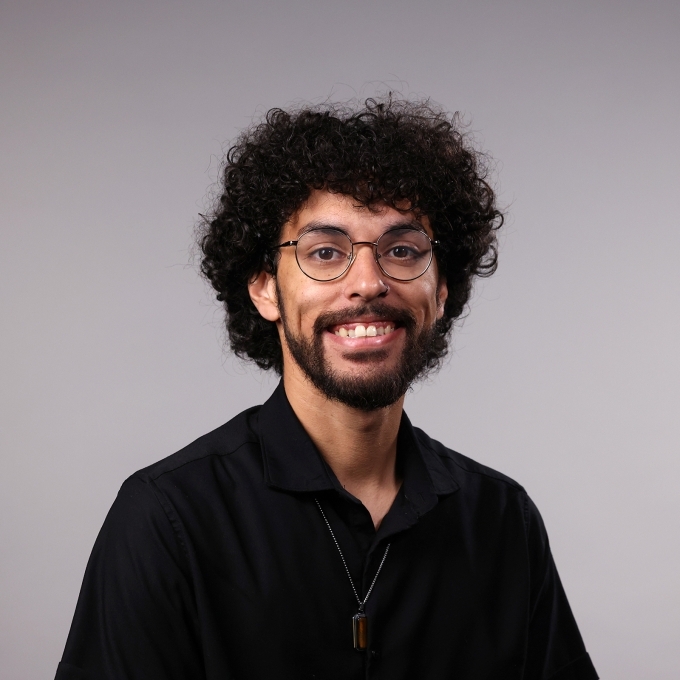 a man with curly dark hair wearing glasses and a black shirt