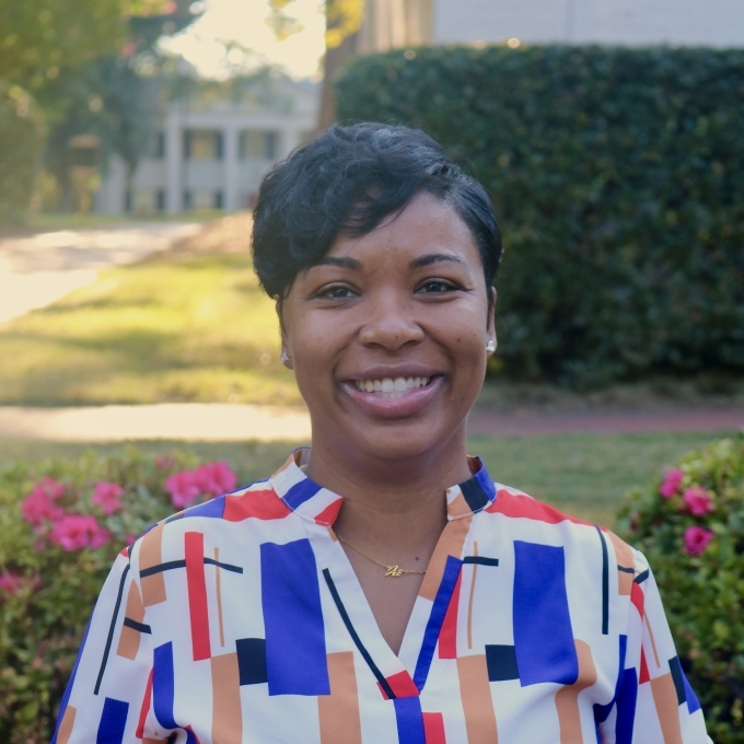 a Black woman with short dark hair wearing a blue, white and red top